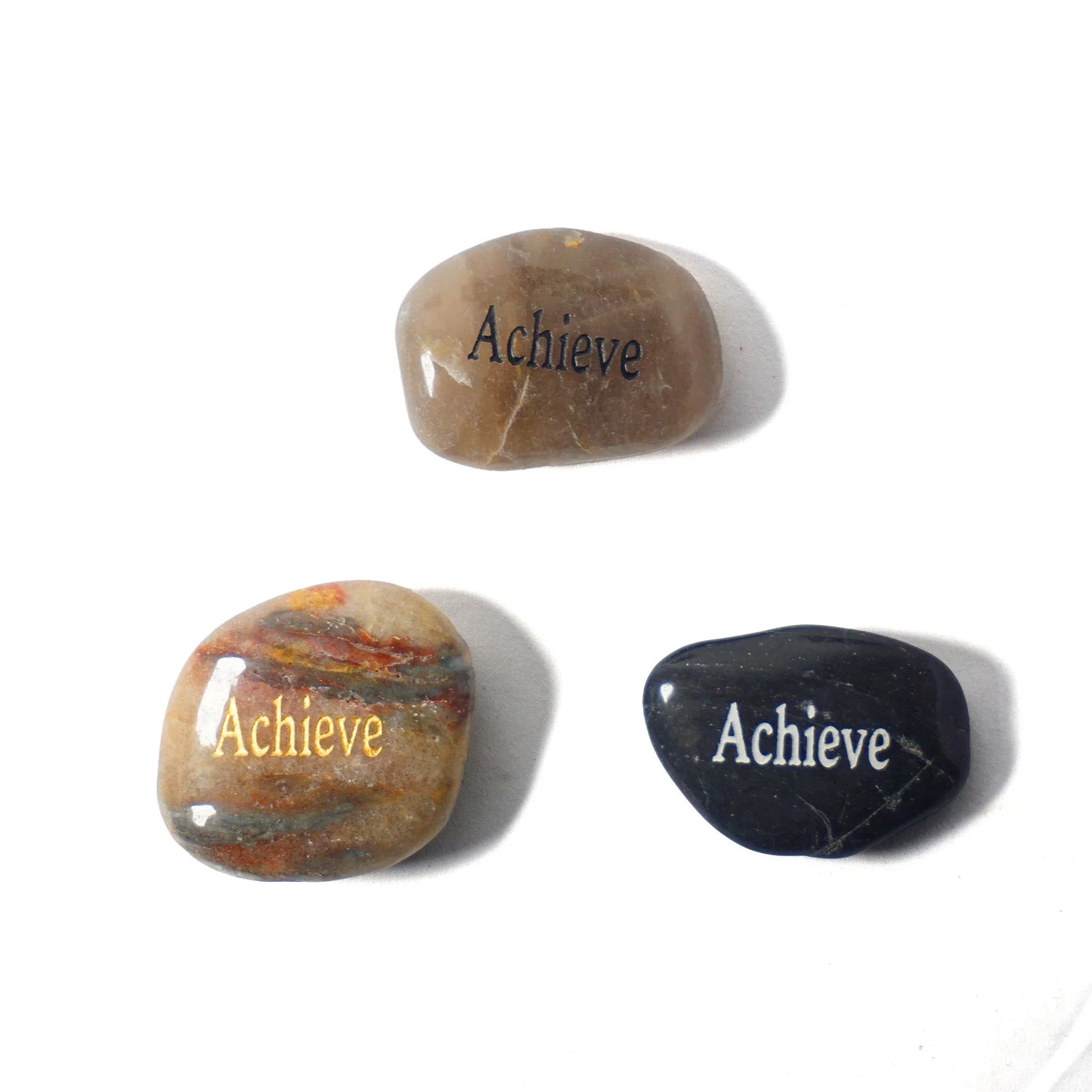 Three stones with 'Achieve' engraved on them on a white background