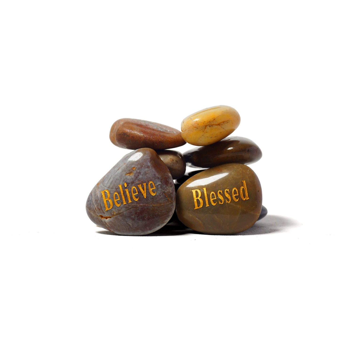 Stack of stones with 'Believe' and 'Blessed' inscriptions on a white background