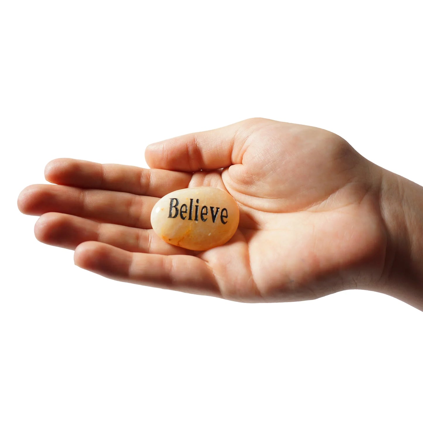 Hand holding a stone with 'Believe' engraved on it against a white background