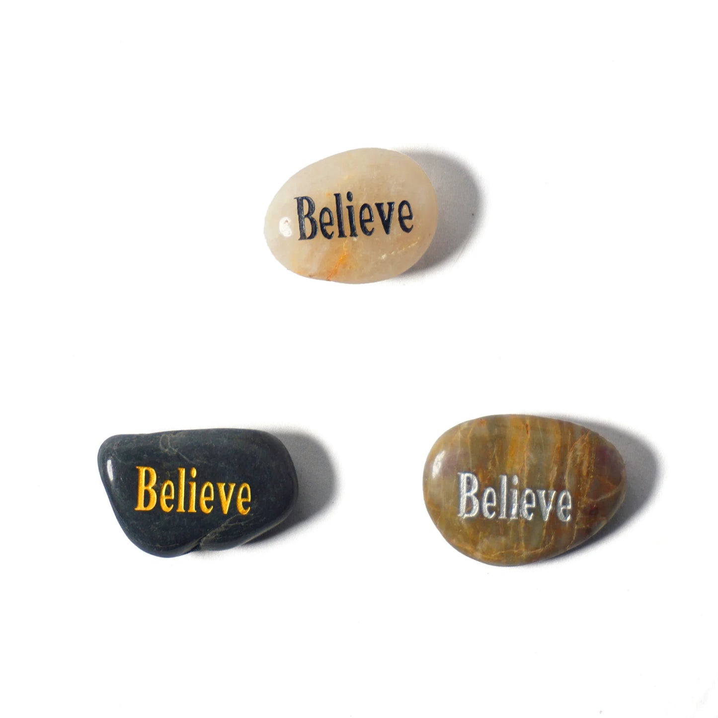 Three stones with 'Believe' engraved on them on a white background