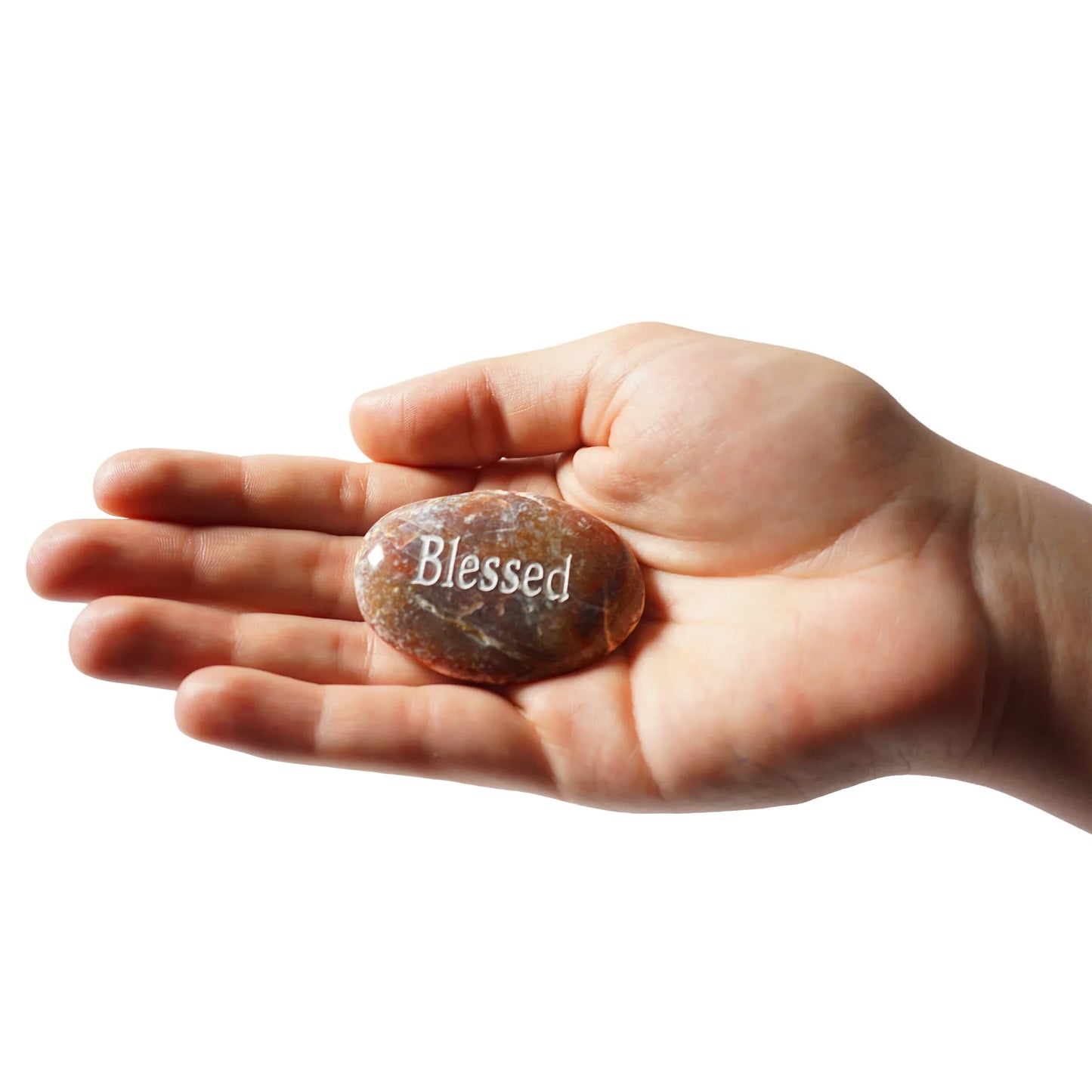 Hand holding a stone with 'Blessed' engraved on it against a white background