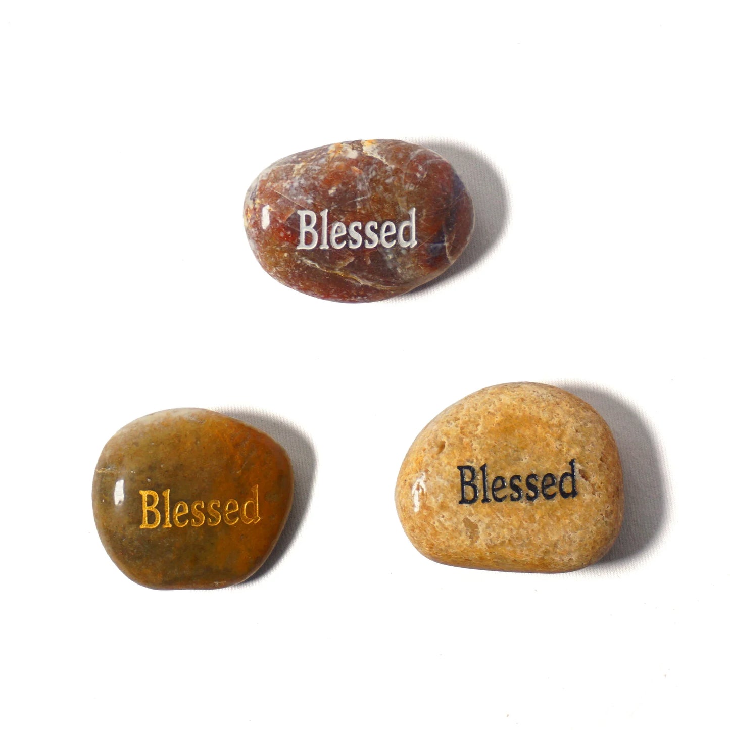 Three stones with 'Blessed' engraved on them on a white background