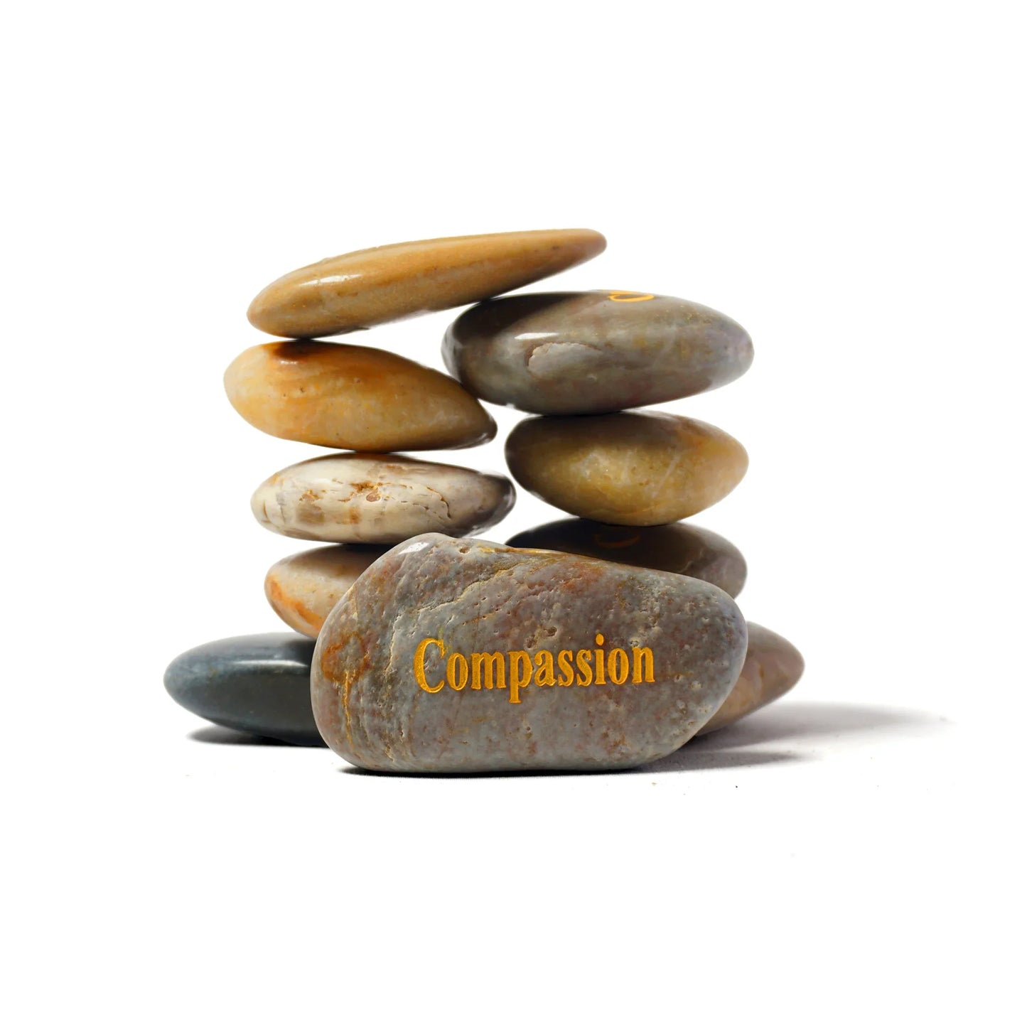 Stack of stones with 'Compassion' engraved on a white background