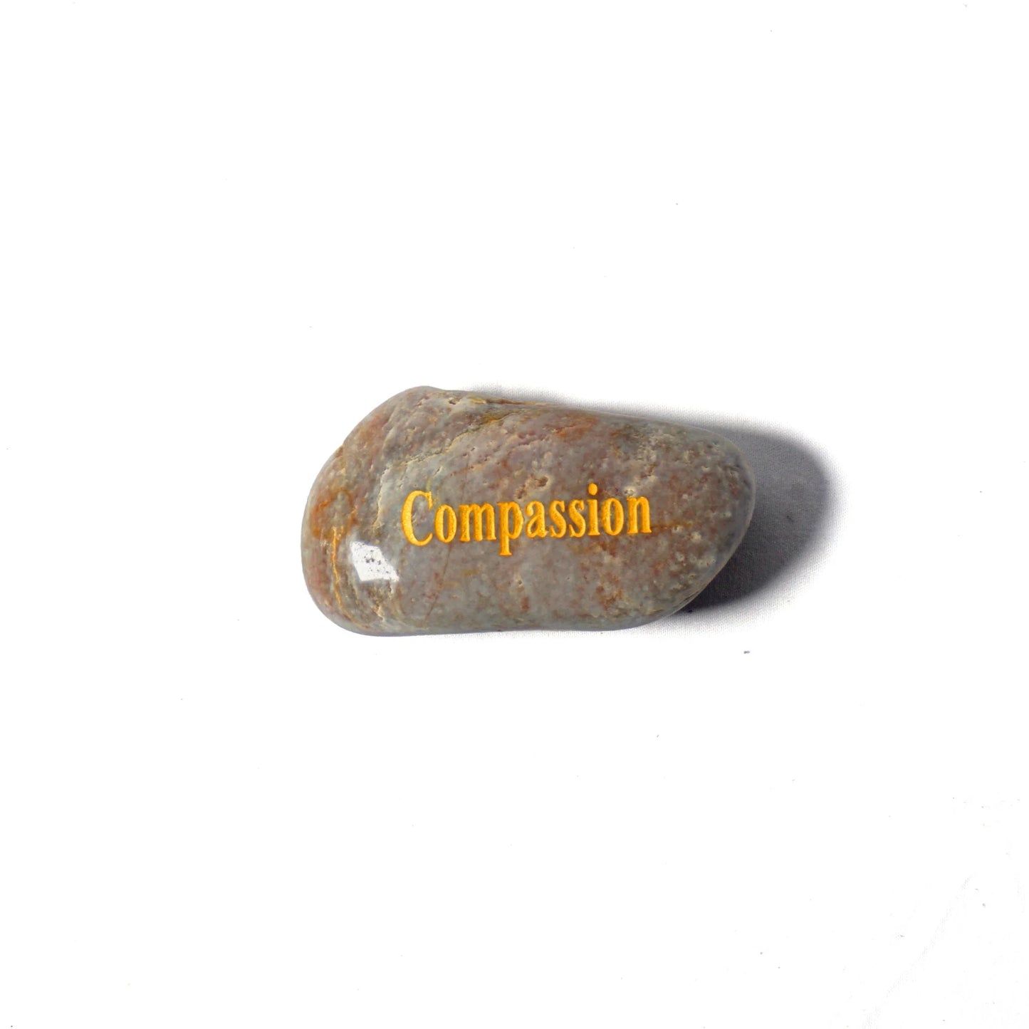 Rounded stone with 'Compassion' engraved on a white background