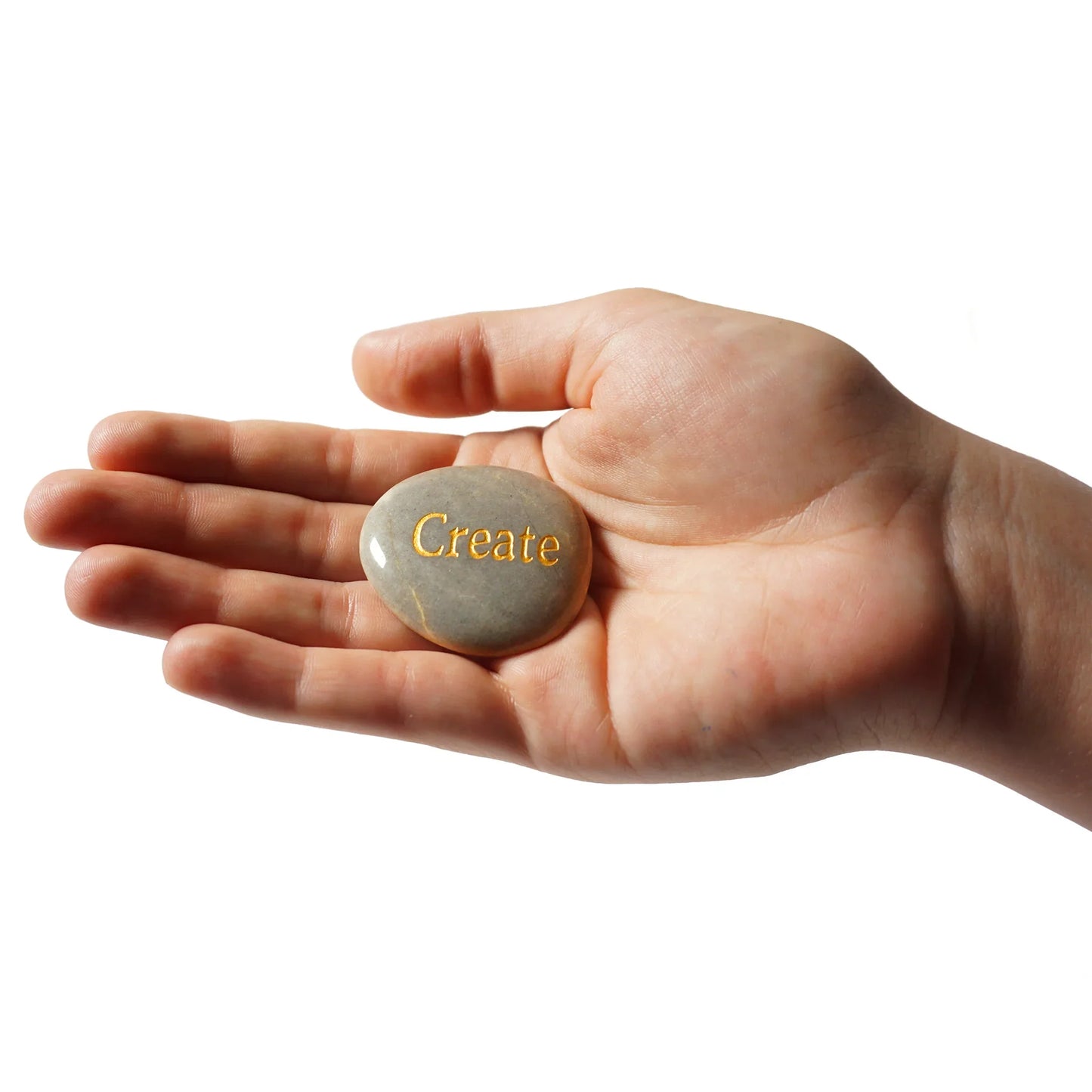 Hand holding a stone with 'Create' engraved on it against a white background