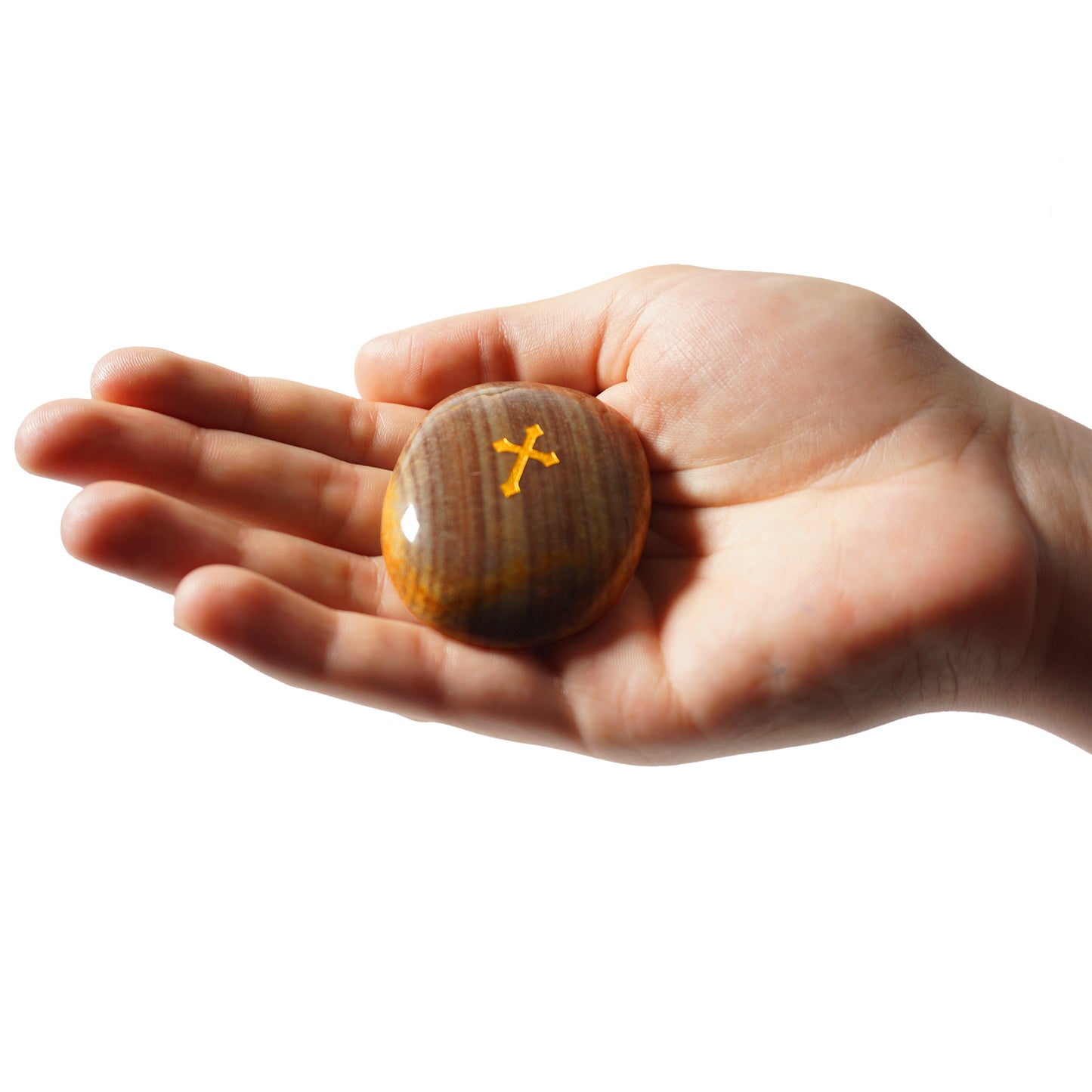 Hand holding a wooden ball with a cross symbol on a white background