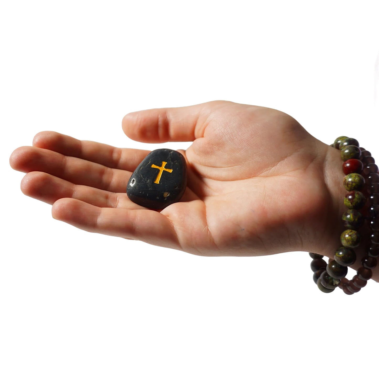Hand holding a stone with a cross symbol on a white background