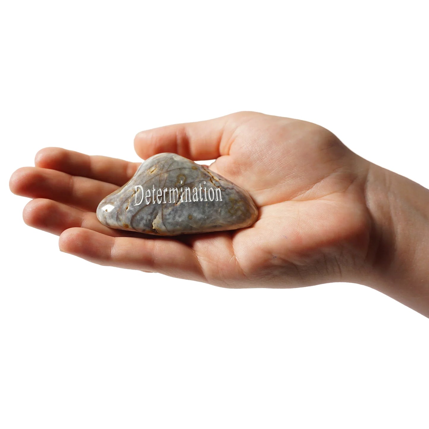 Hand holding a rock with 'Determination' engraved on it against a white background