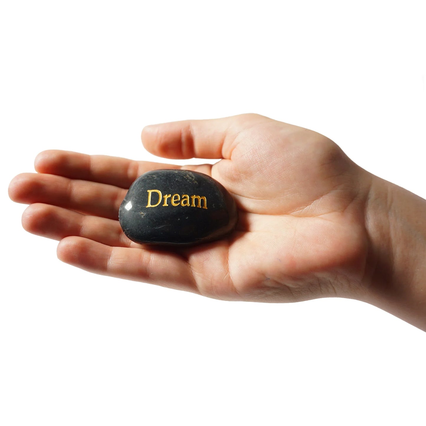 Hand holding a black stone with 'Dream' engraved on it against a white background