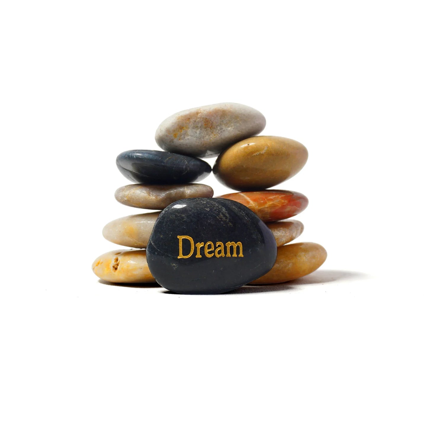 Stack of multicolored stones with a black stone in the center displaying the word 'Dream' on a white background.