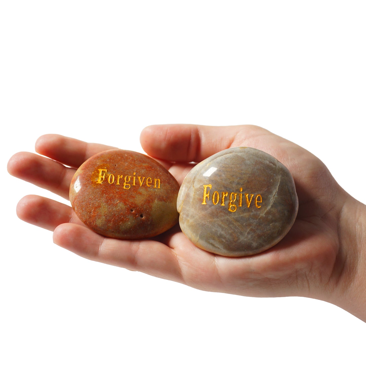 Hand holding two stones with 'Forgiven' and 'Forgive' engraved on them against a white background
