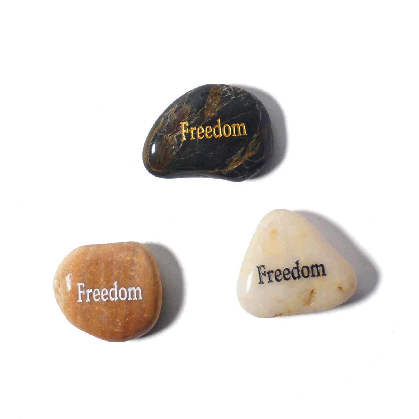 Three stones with 'Freedom' engraved on them on a white background