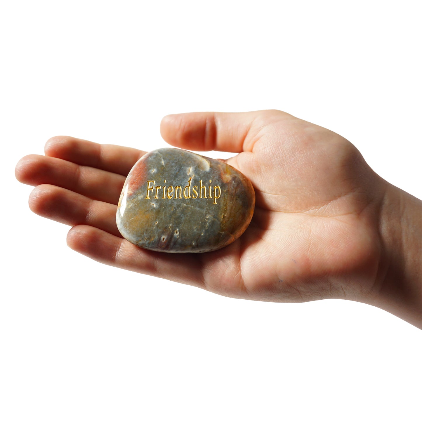 Hand holding a stone with 'Friendship' engraved on a white background