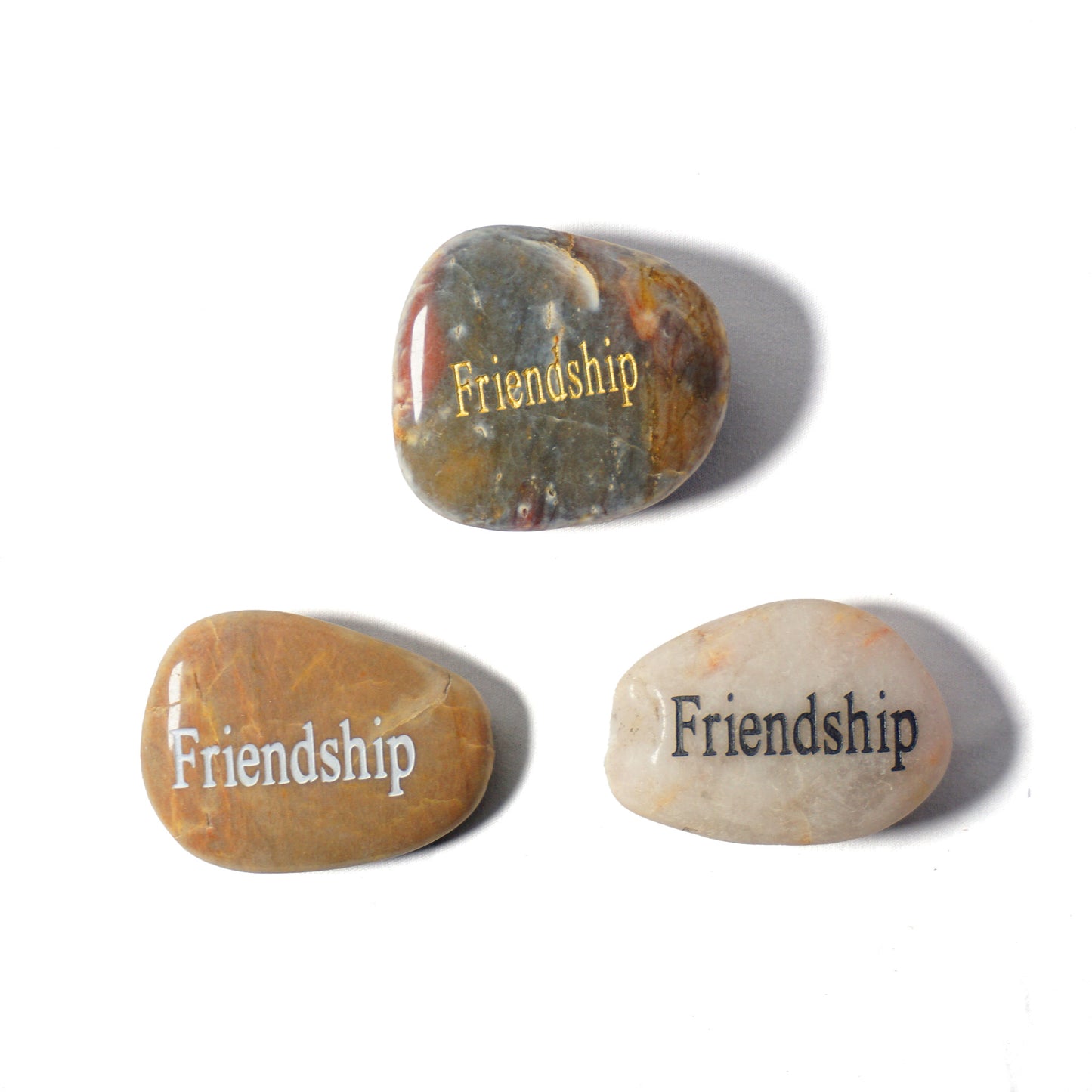 Three stones with 'Friendship' engraved on them on a white background
