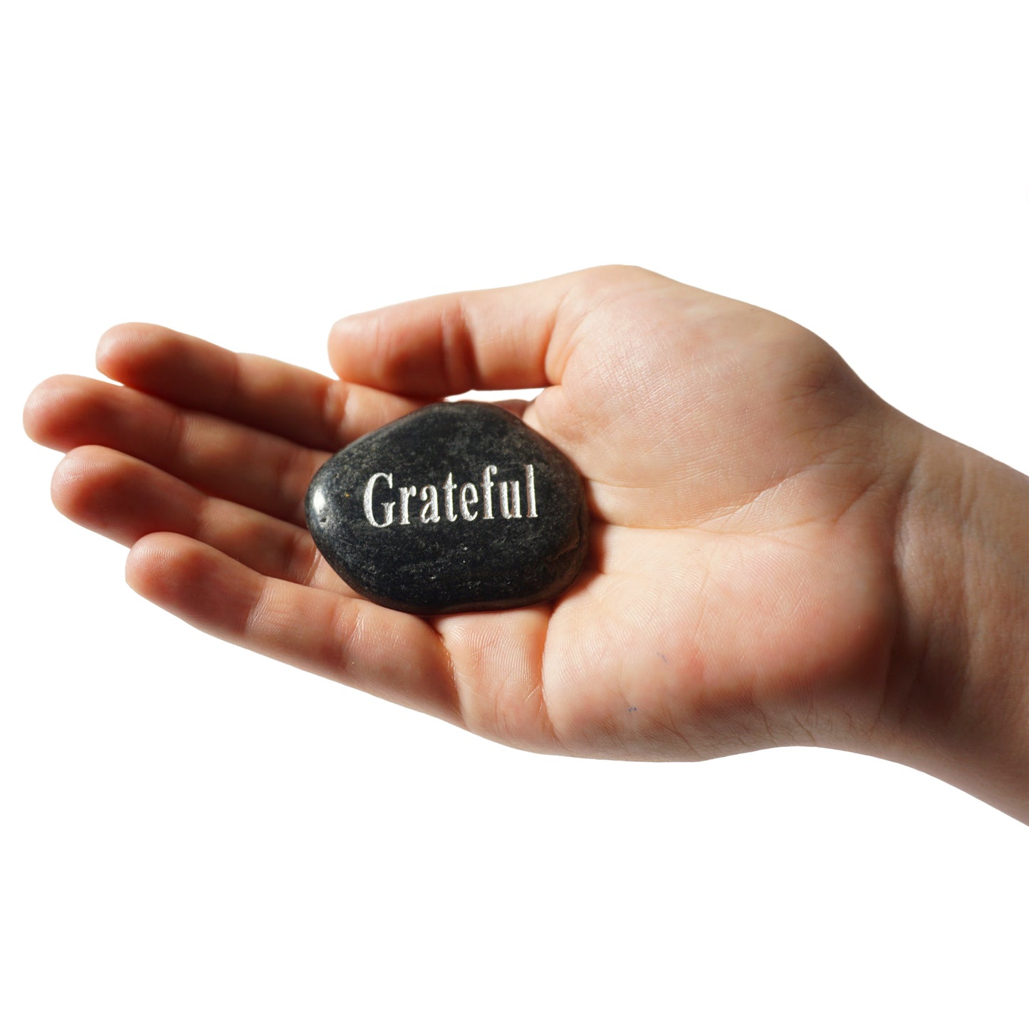 Hand holding a stone with 'Grateful' engraved on it against a white background