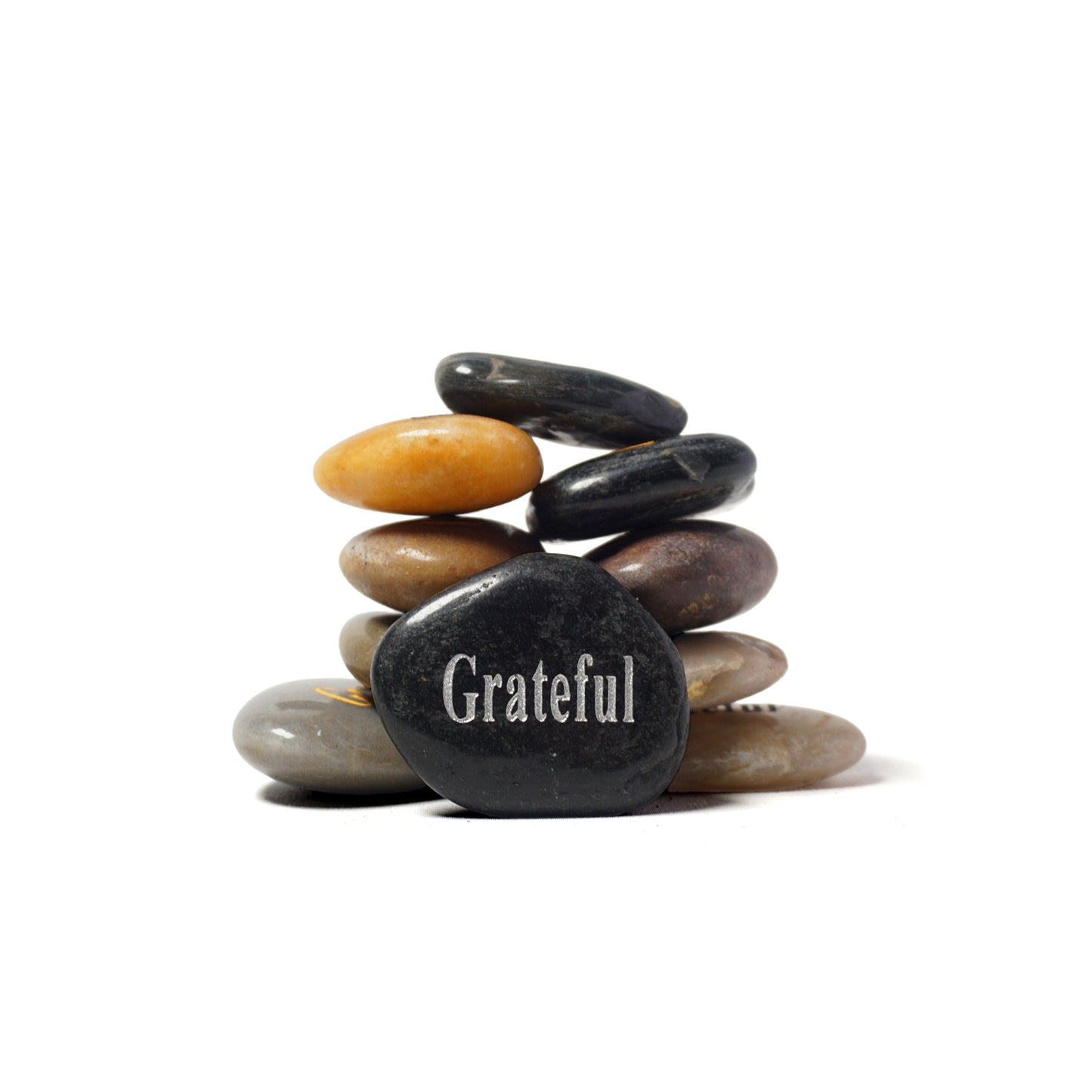 Stack of stones with a black stone in the center displaying the word 'Grateful' on a white background