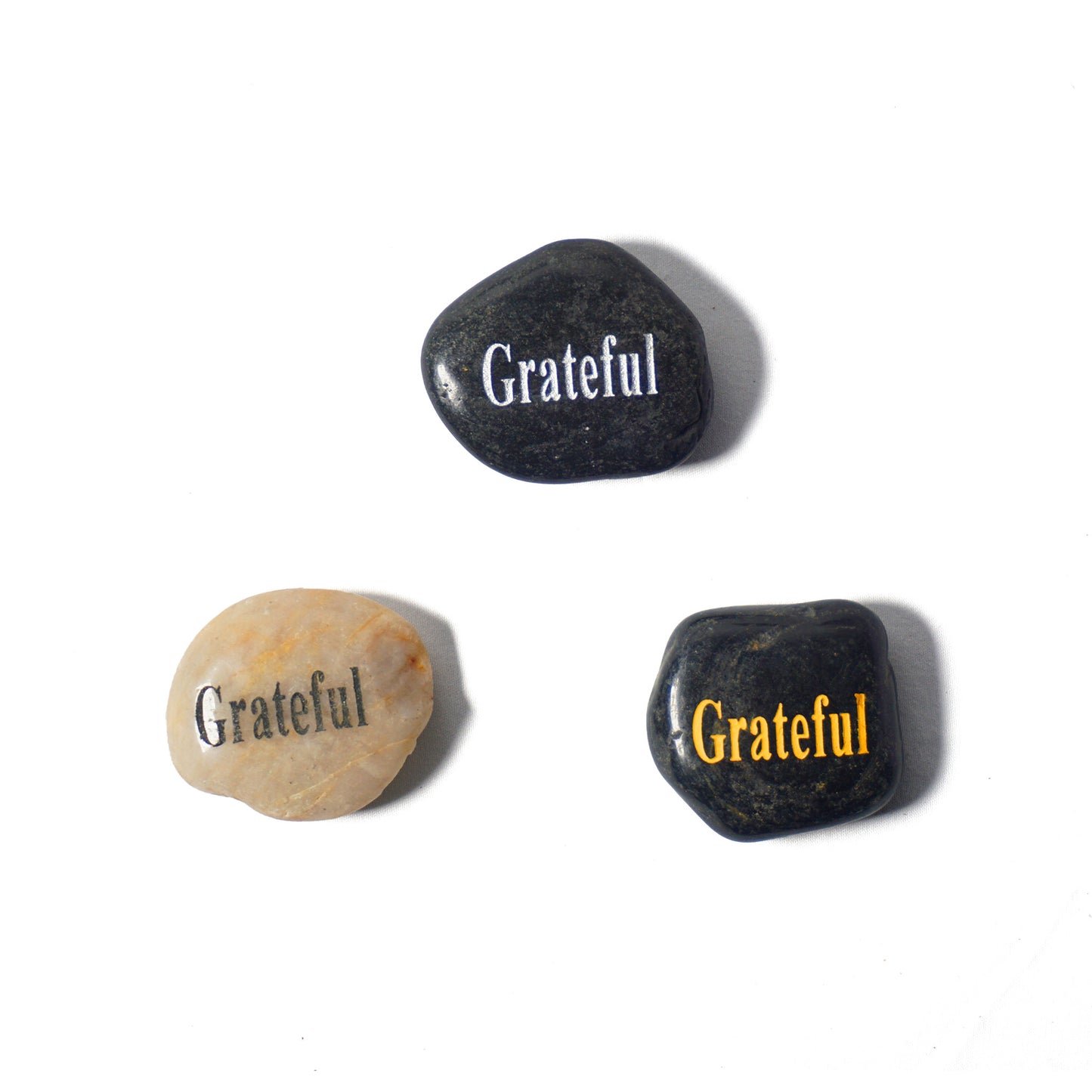 Three stones with 'Grateful' engraved on them on a white background