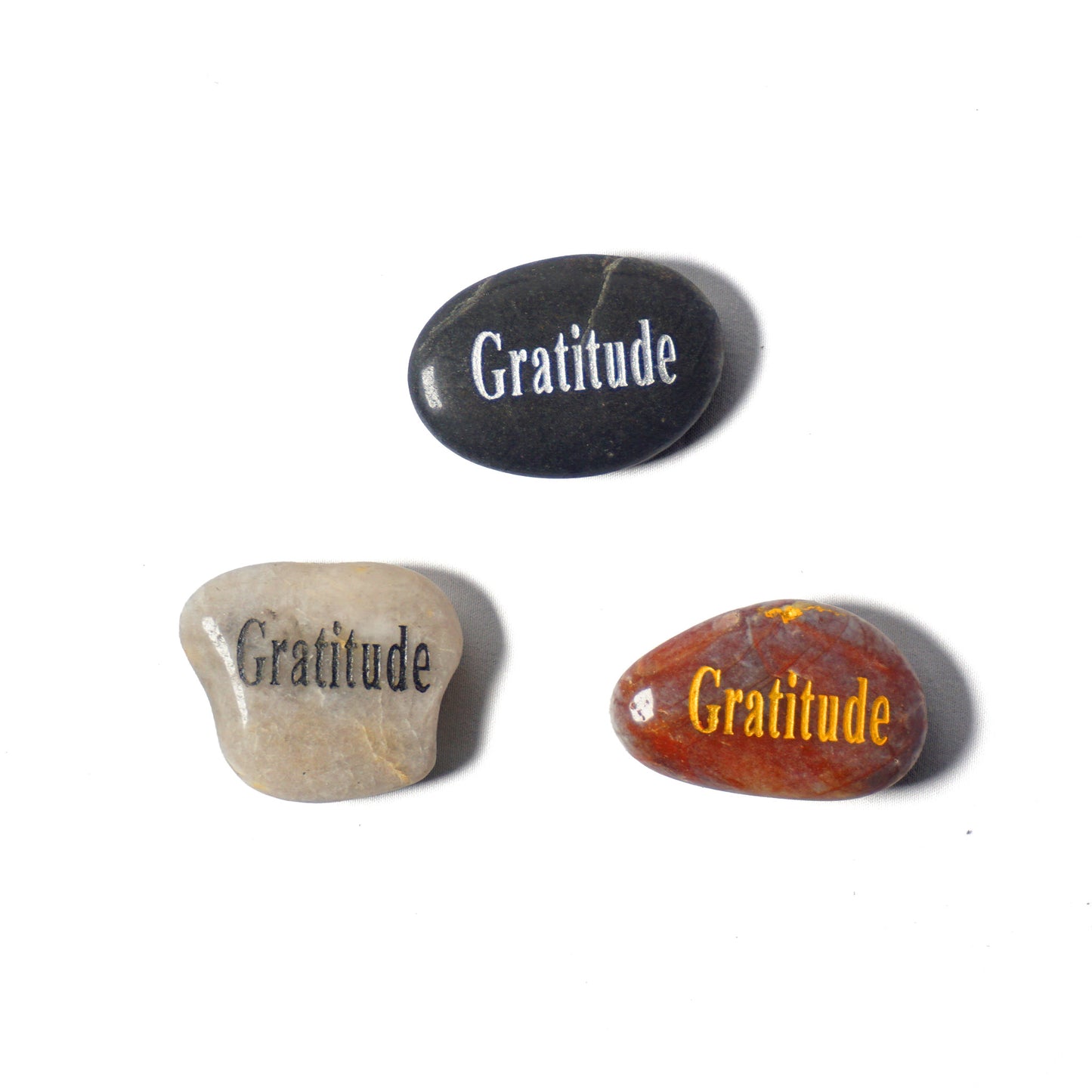 Three stones with 'Gratitude' engraved on them on a white background