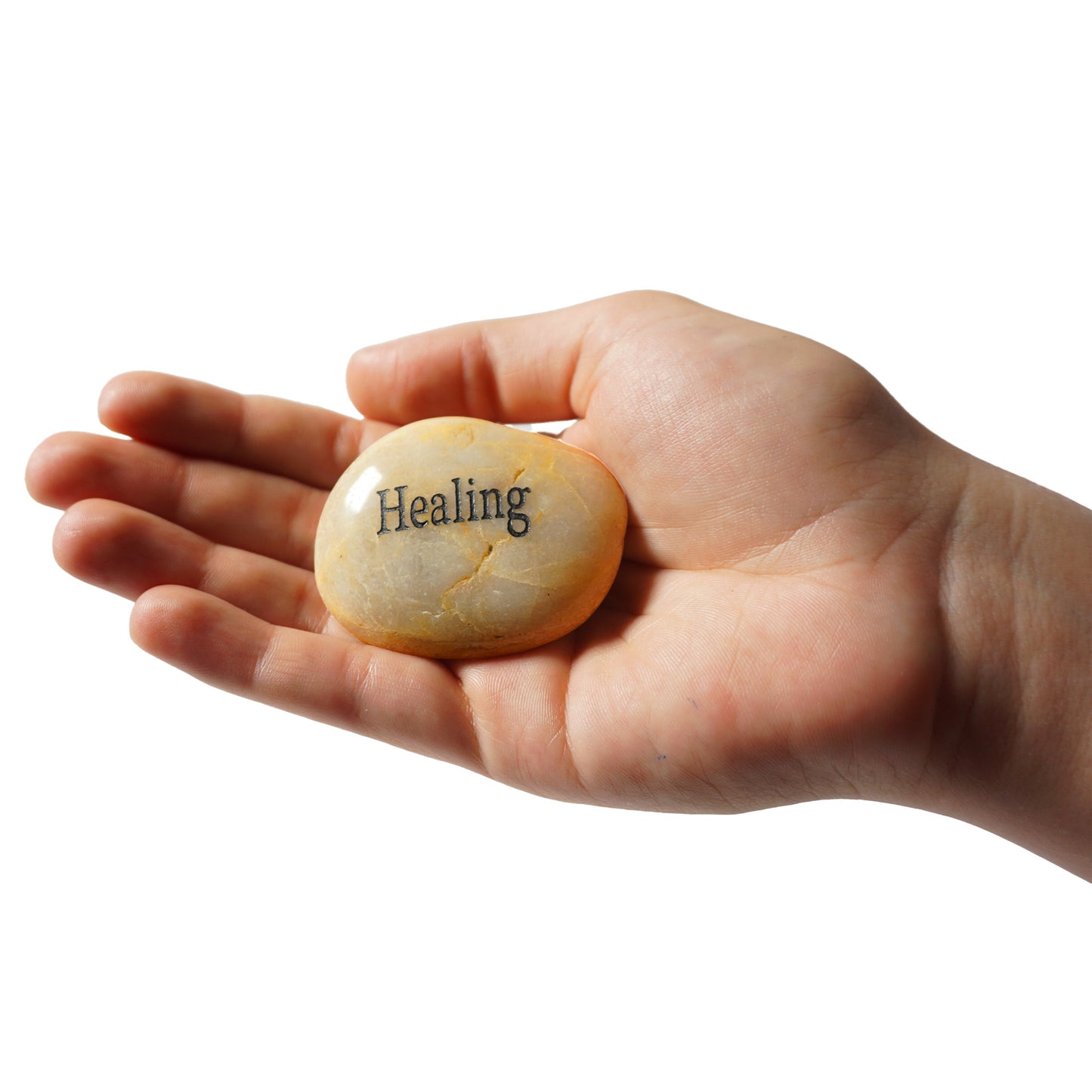 Hand holding a stone with 'Healing' engraved on it against a white background