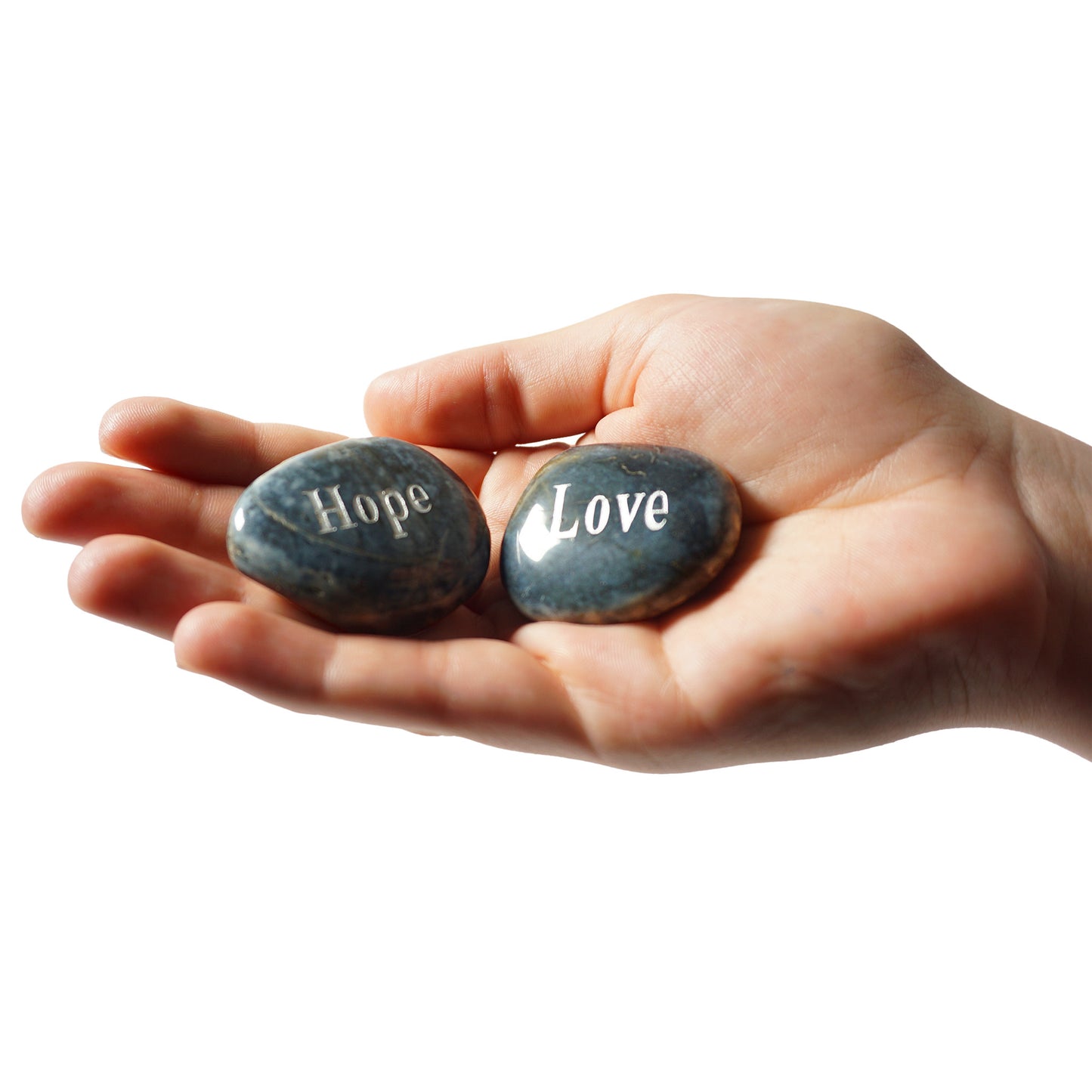 Hand holding two stones engraved with 'Hope' and 'Love' on a white background