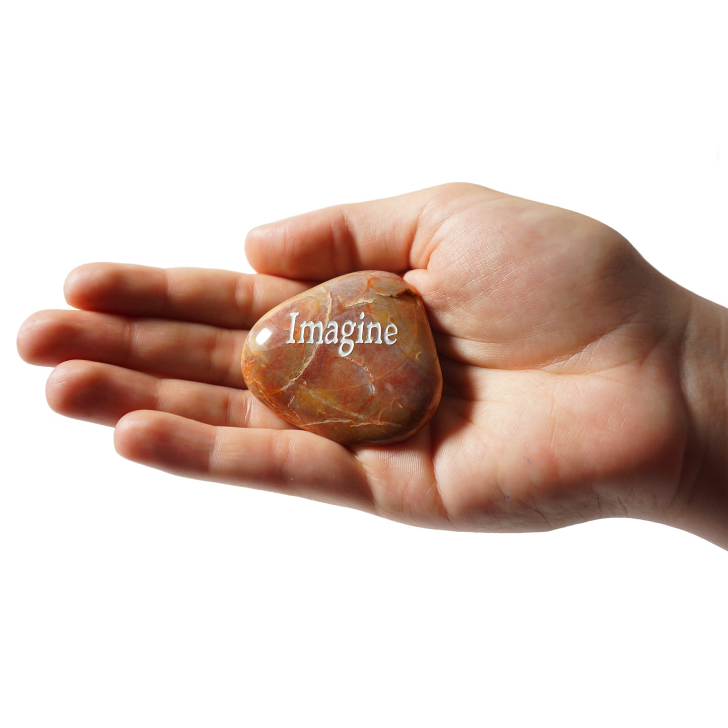 Hand holding a stone with 'Imagine' engraved on it against a white background