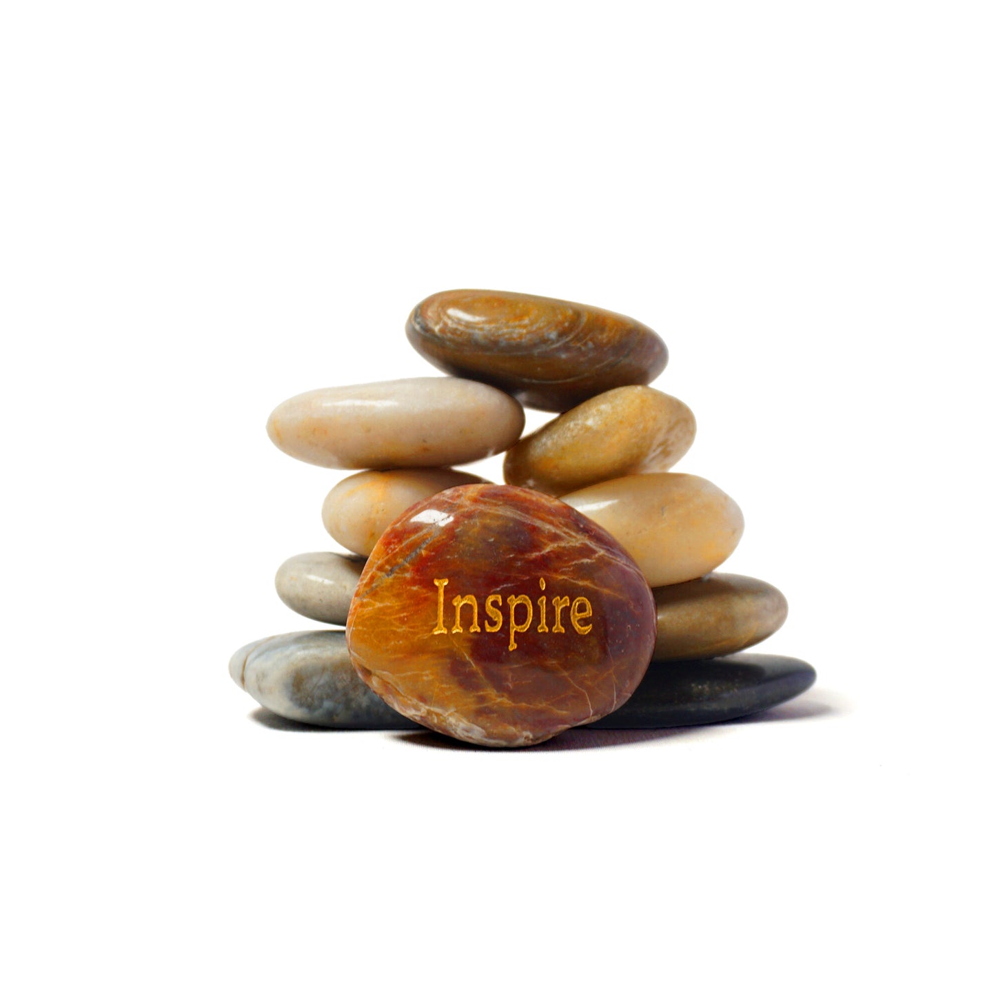 Stack of stones with 'Inspire' engraved on one of them against a white background
