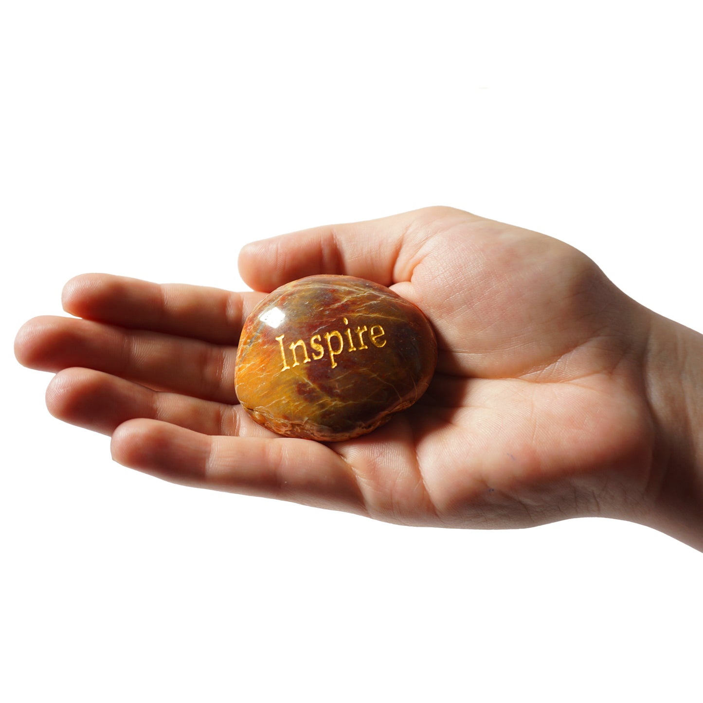 Hand holding a rock with 'Inspire' engraved on it against a white background