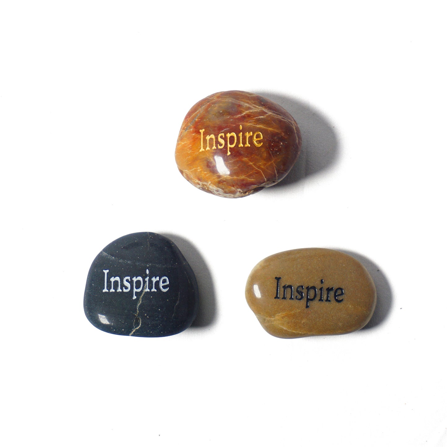 Three stones with 'Inspire' engraved on them on a white background