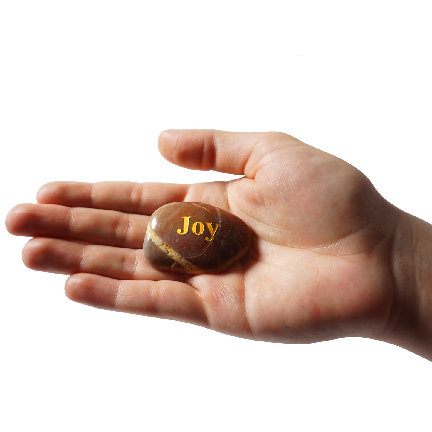 Hand holding a rock with 'Joy' engraved on it against a white background