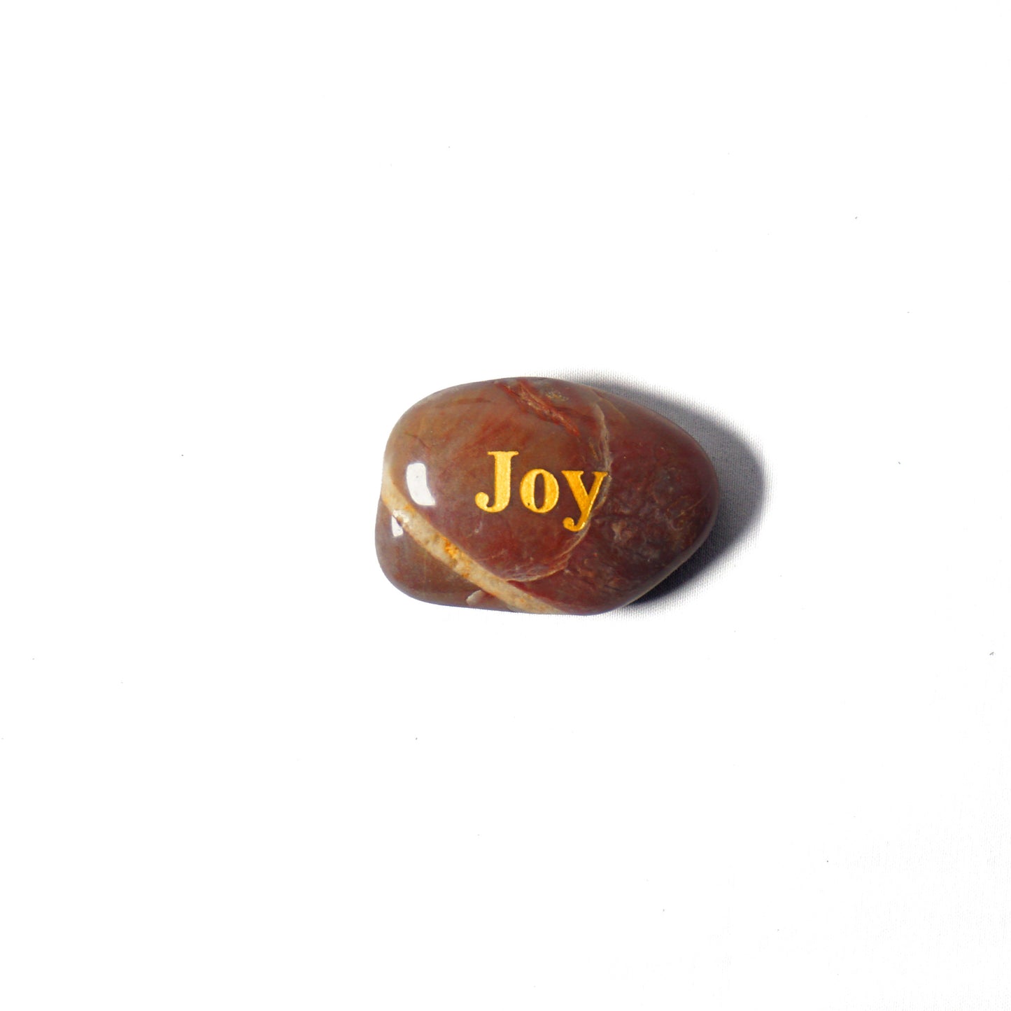 Brown stone with 'Joy' engraved on a white background
