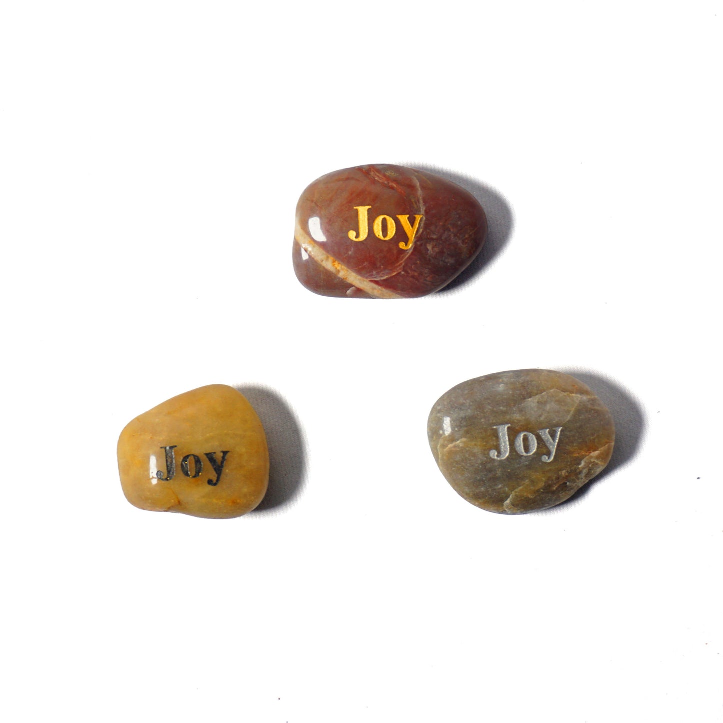 Three stones with 'Joy' engraved on them on a white background