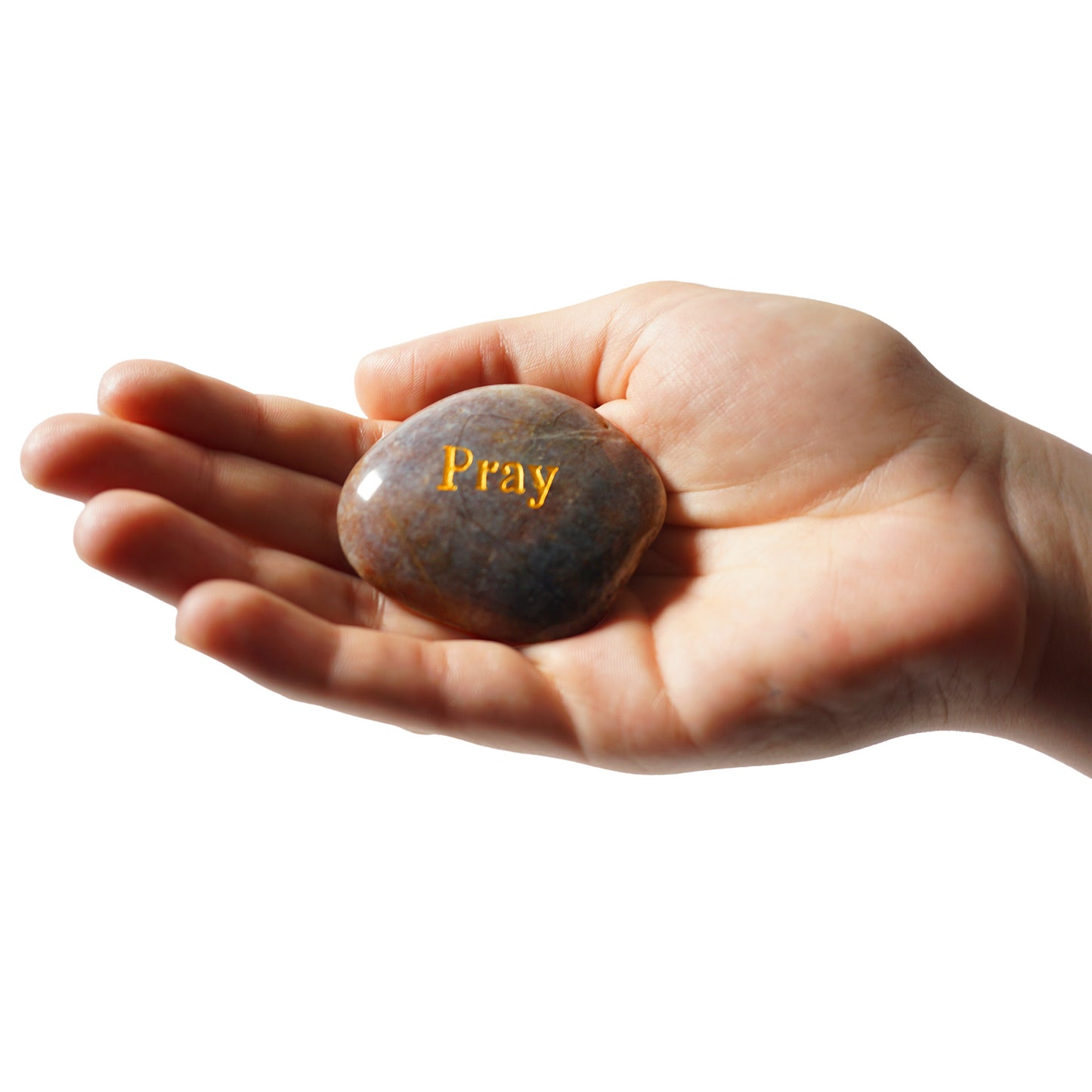 Hand holding a stone with 'Pray' engraved on it against a white background
