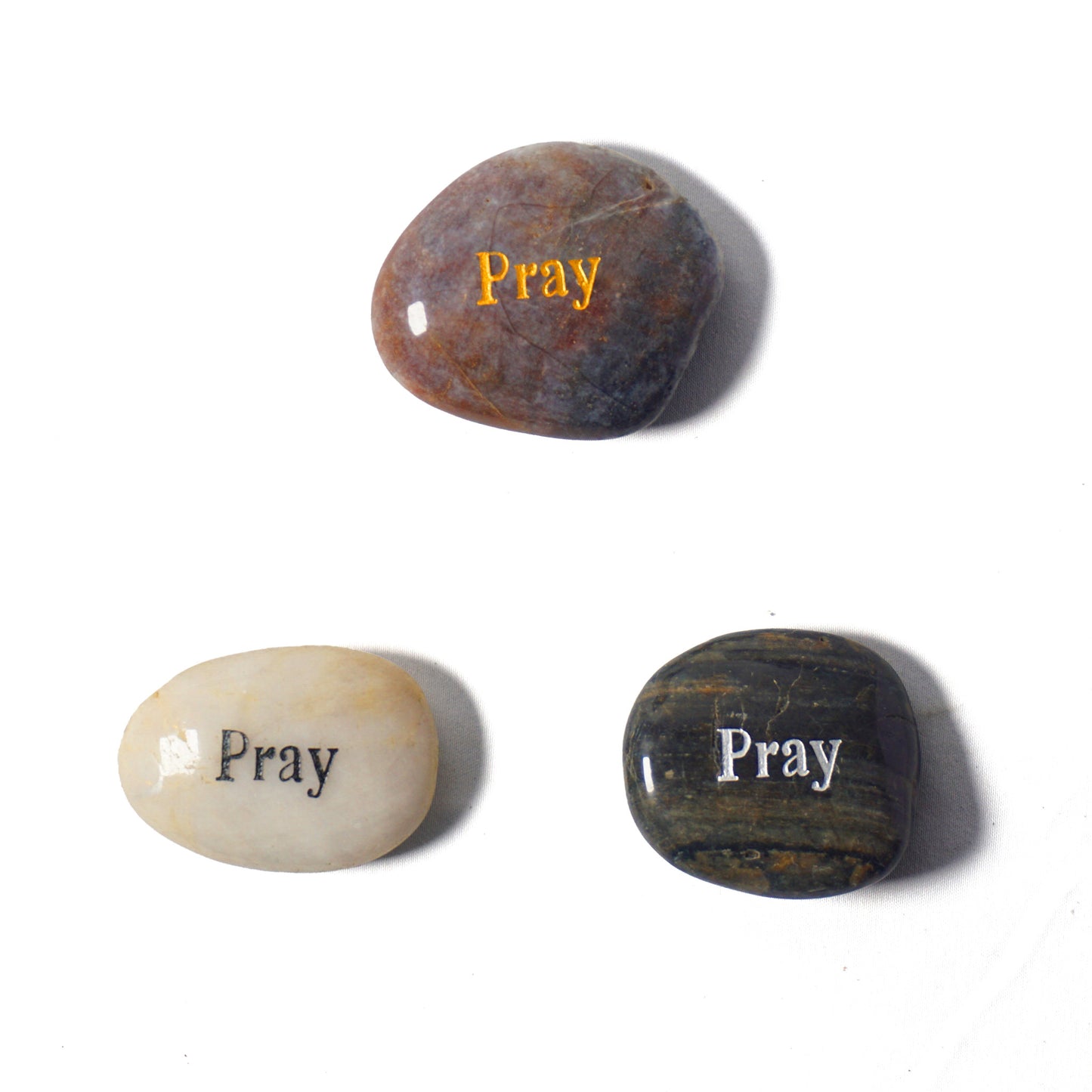 Three stones with 'Pray' engraved on them on a white background