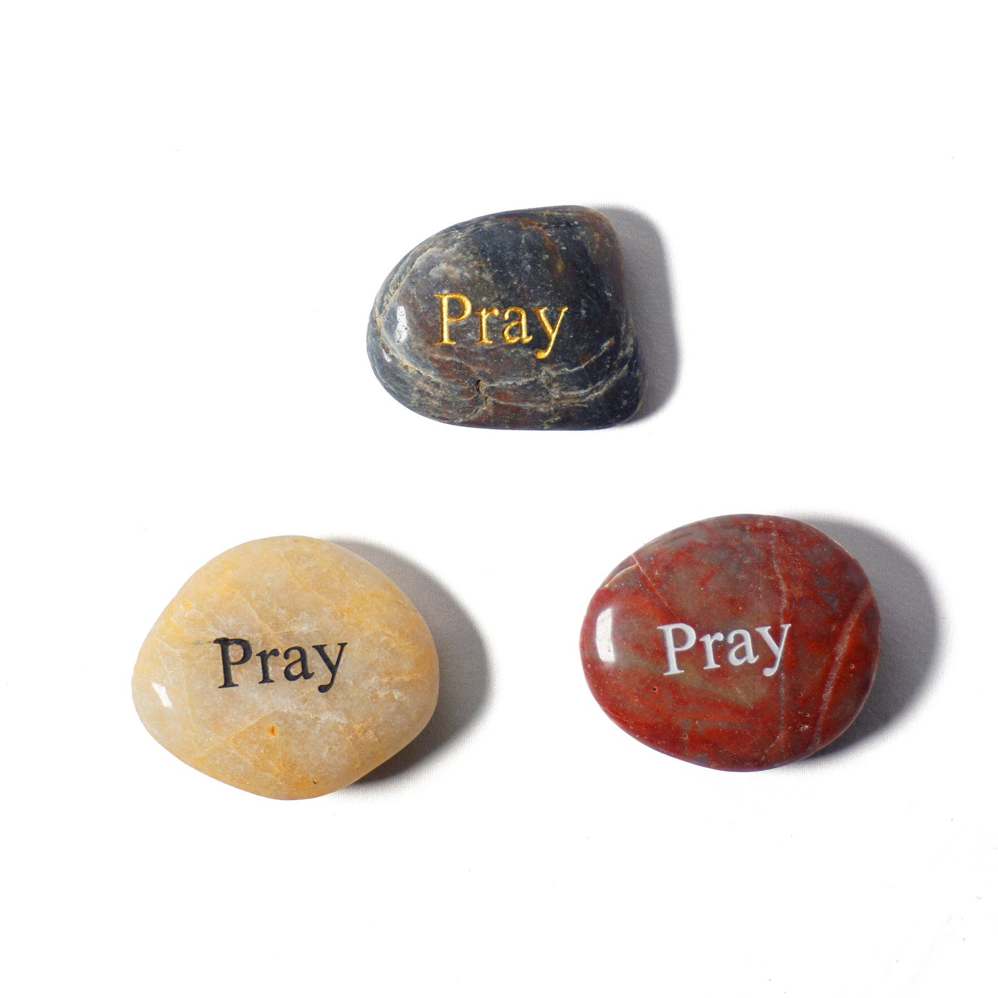 Three stones with 'Pray' engraved on them on a white background