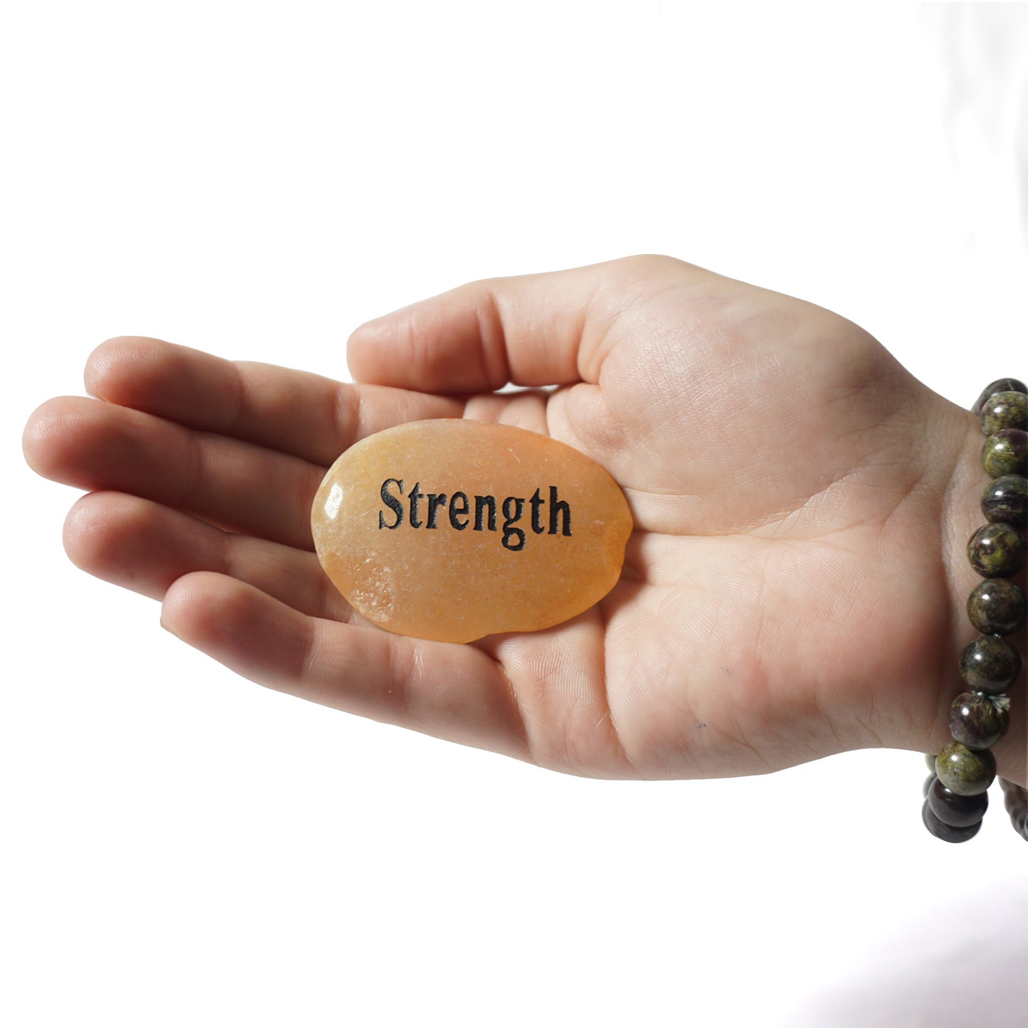 Hand holding a stone with 'Strength' engraved on it against a white background