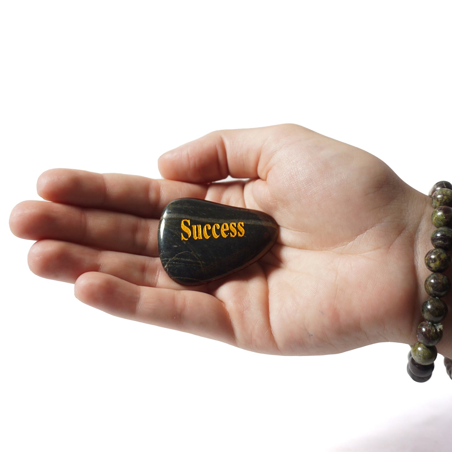 Hand holding a stone with 'Success' engraved on it against a white background