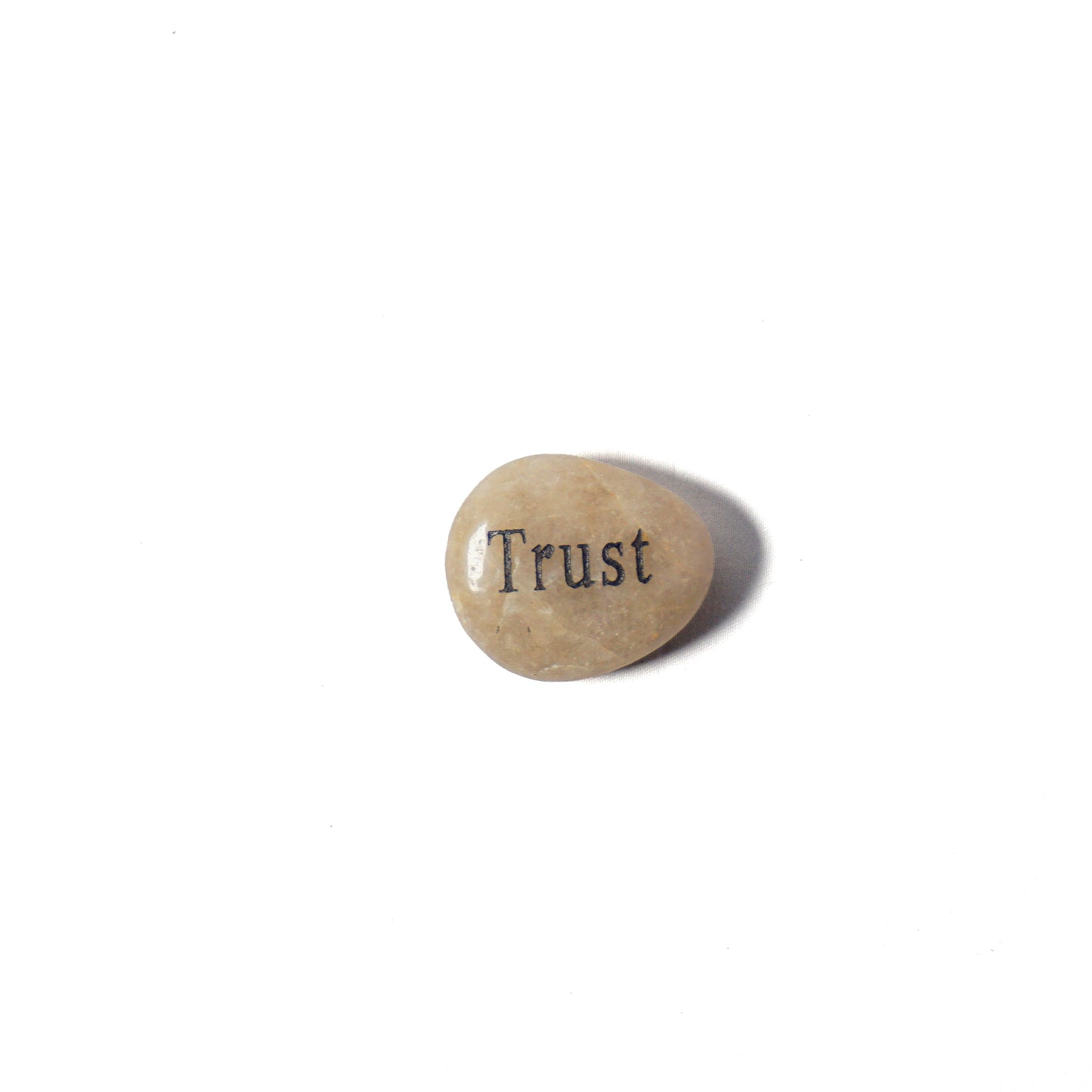 Small stone with 'Trust' engraved on a white background