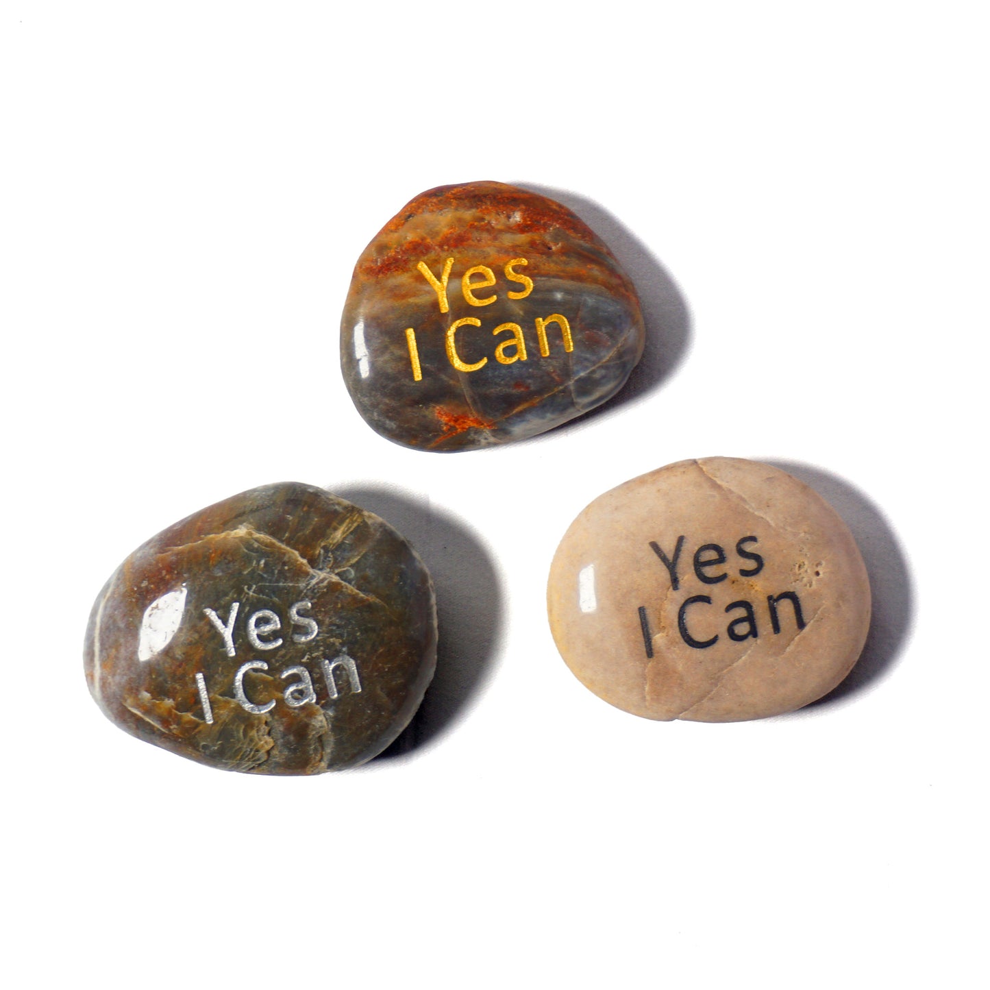 Three stones with 'Yes I Can' engraved on them on a white background