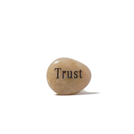Rounded stone with 'Trust' engraved on a white background