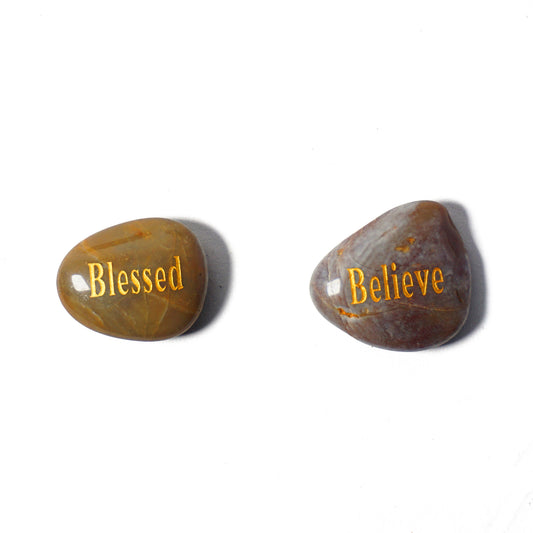 Two stones with 'Blessed' and 'Believe' engraved on them against a white background