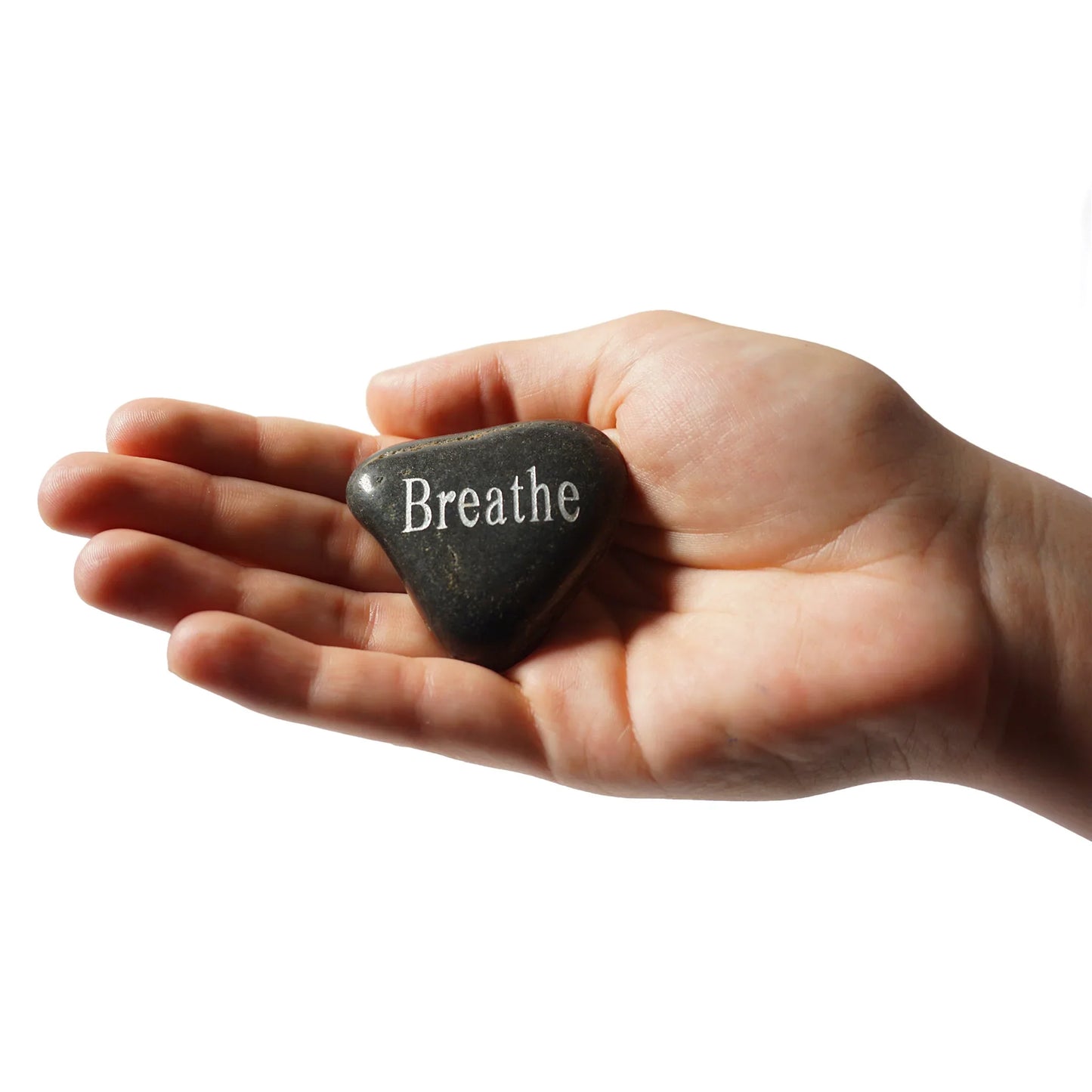 Hand holding a stone with 'Breathe' engraved on it against a white background