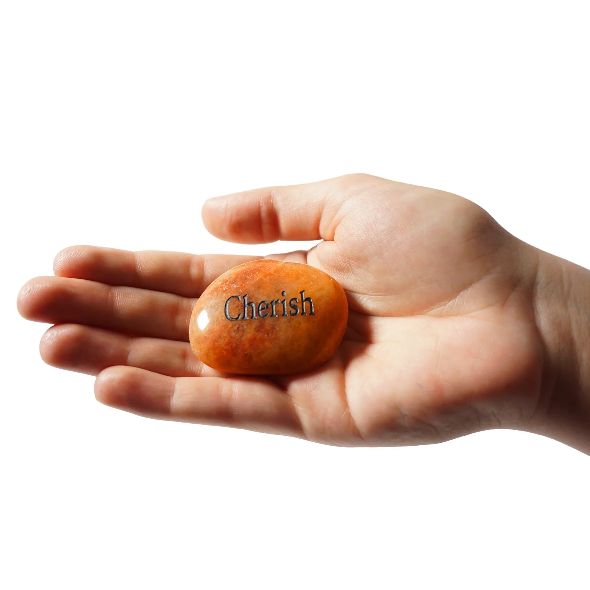 Hand holding a stone with 'Cherish' engraved on it against a white background