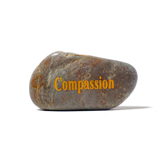 Brown stone with 'Compassion' engraved on a white background