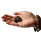Hand holding a stone with a cross symbol on a white background