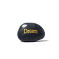 Black stone with 'Dream' engraved in gold on a white background