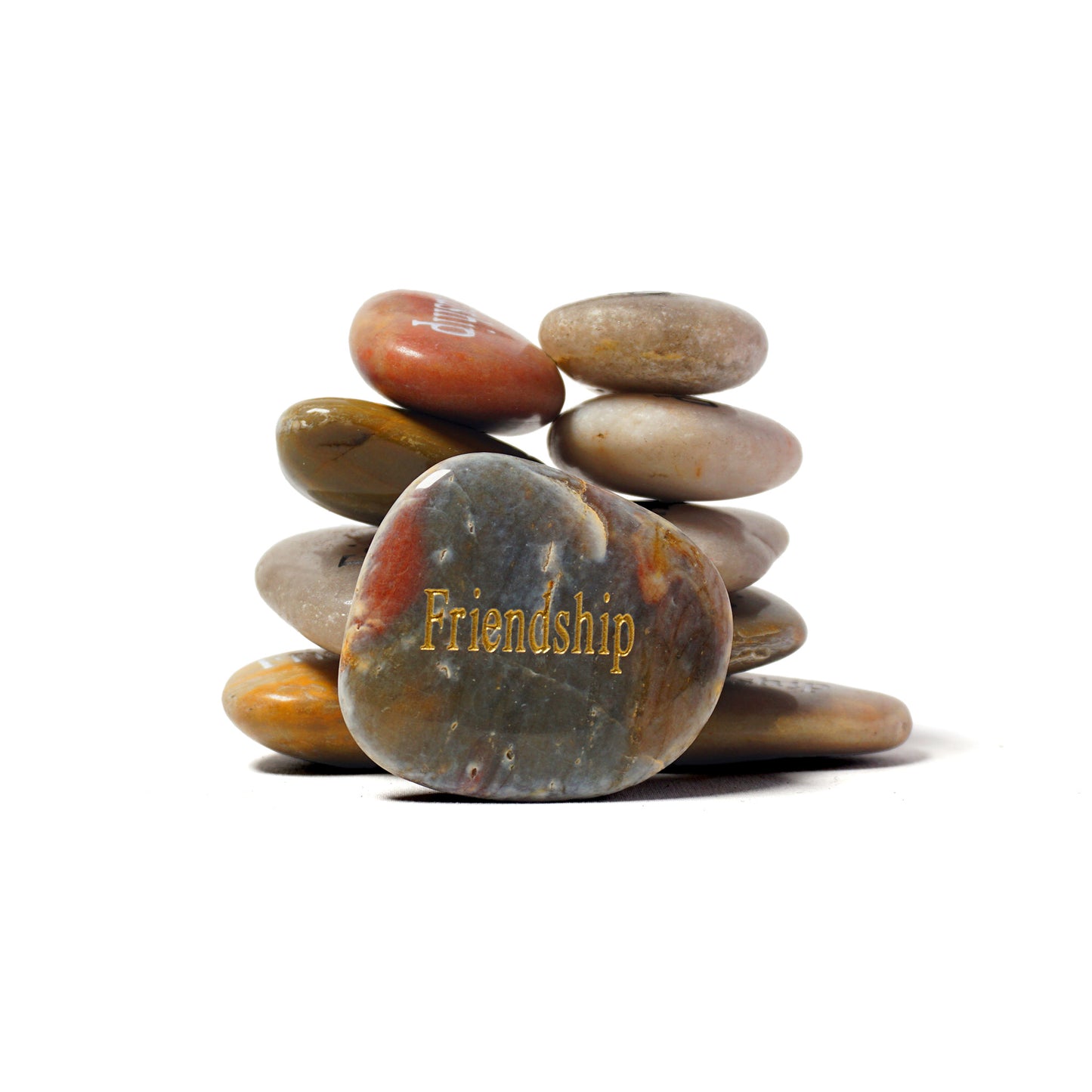 Stack of multicolored stones with 'Friendship' engraved on a white background