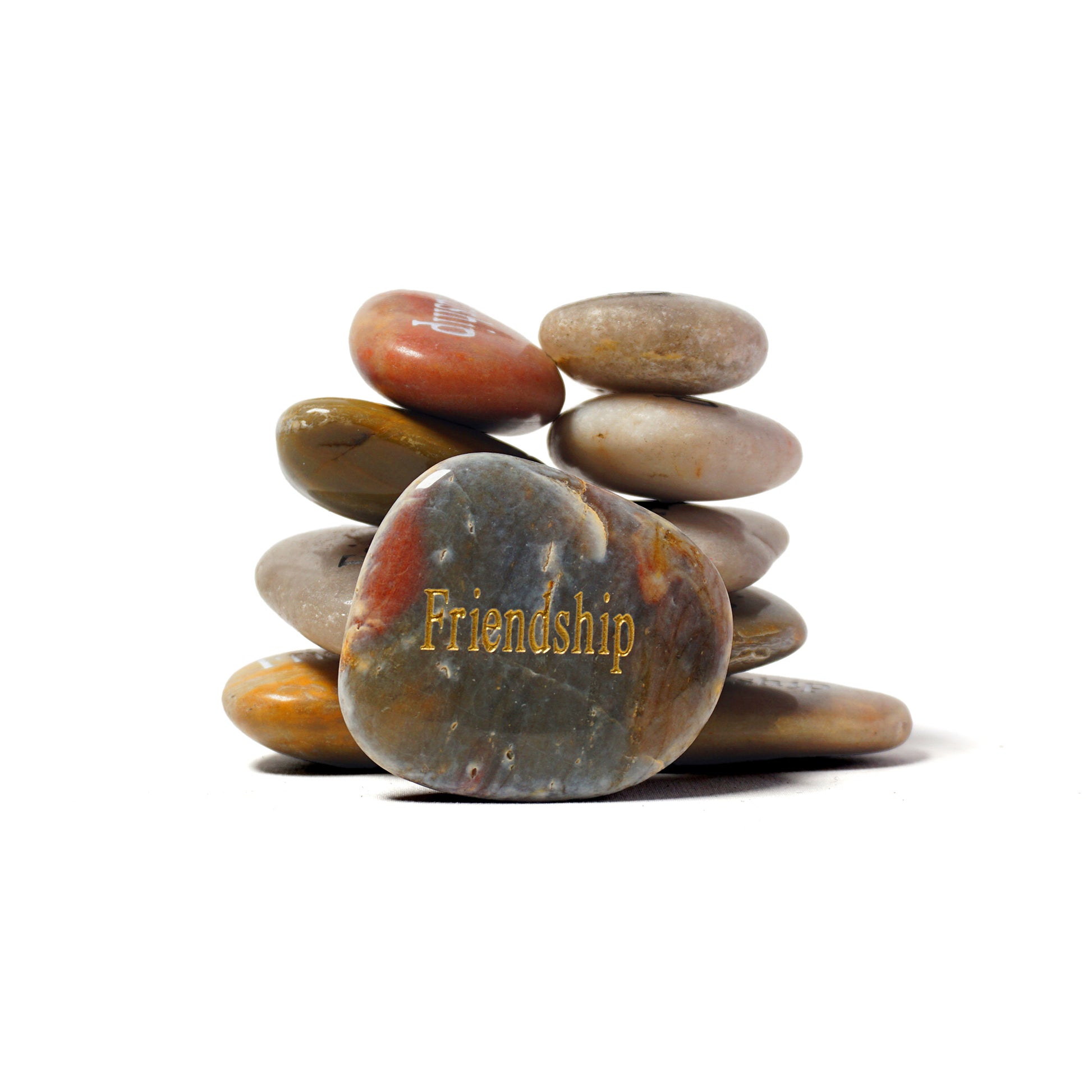 Stack of multicolored stones with 'Friendship' engraved on a white background