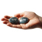 Hand holding two stones engraved with 'Hope' and 'Love' on a white background