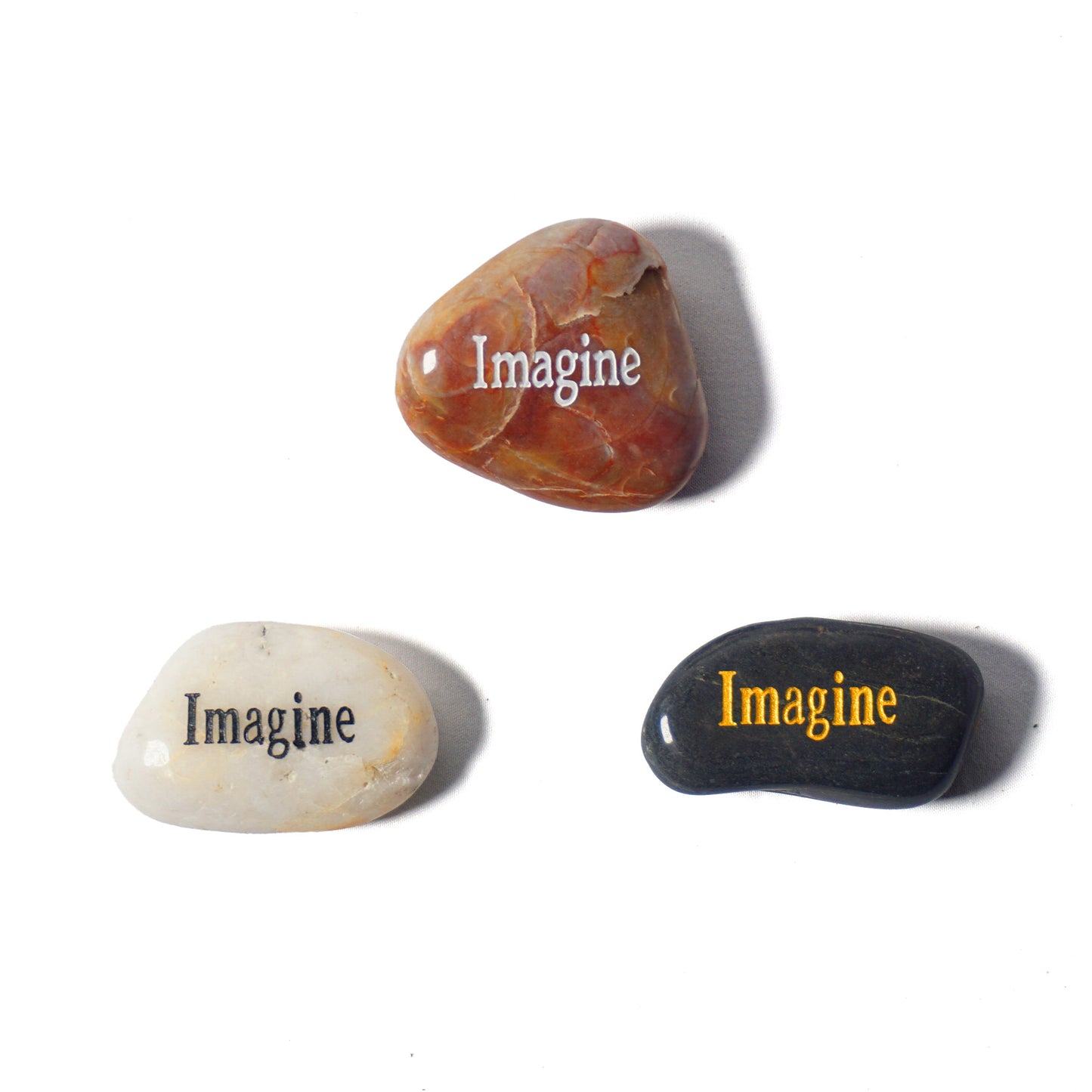 Three stones with 'Imagine' engraved on them on a white background