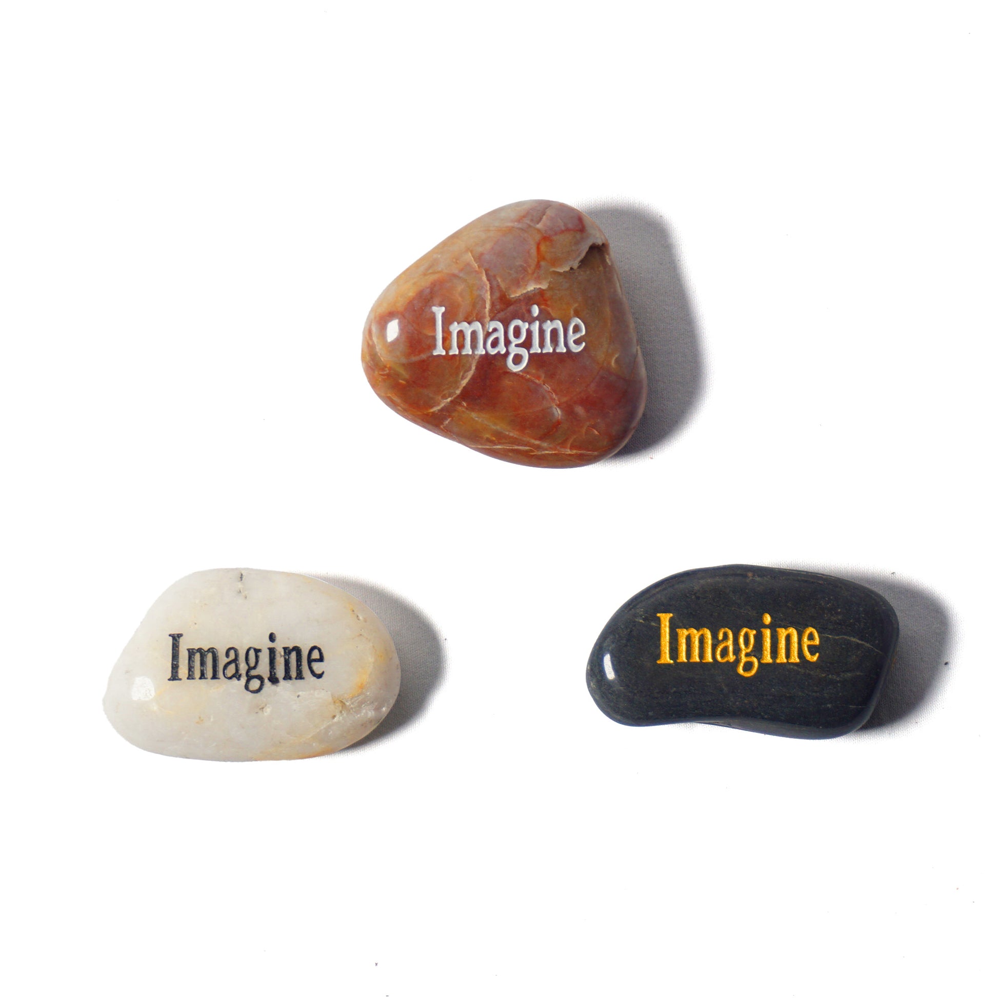 Three stones with 'Imagine' engraved on them on a white background